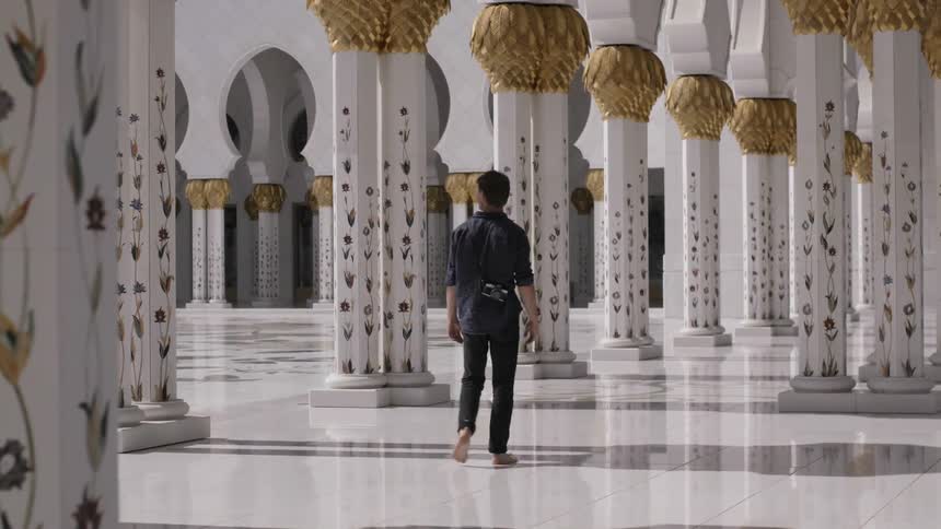 A man walks barefoot near ornate building pillars