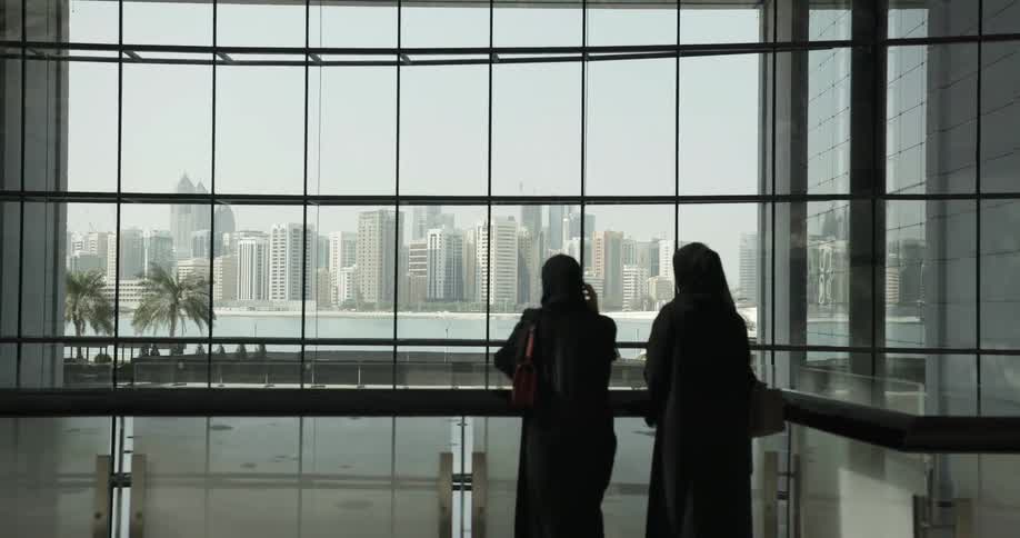 Two women look through paned windows in a city