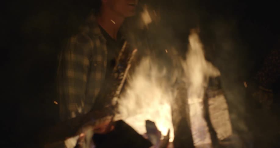 A man and woman hold hands while walking near a bonfire