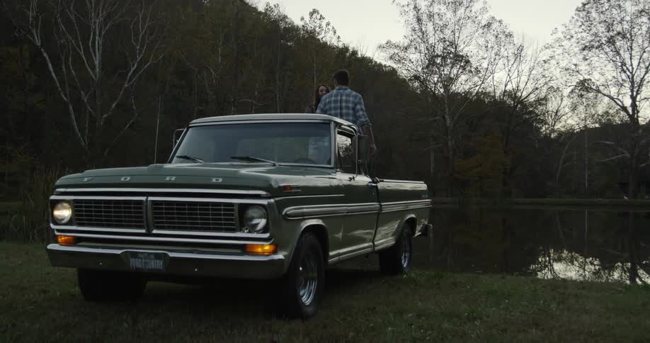 Man and woman dance on a truck next to a lake