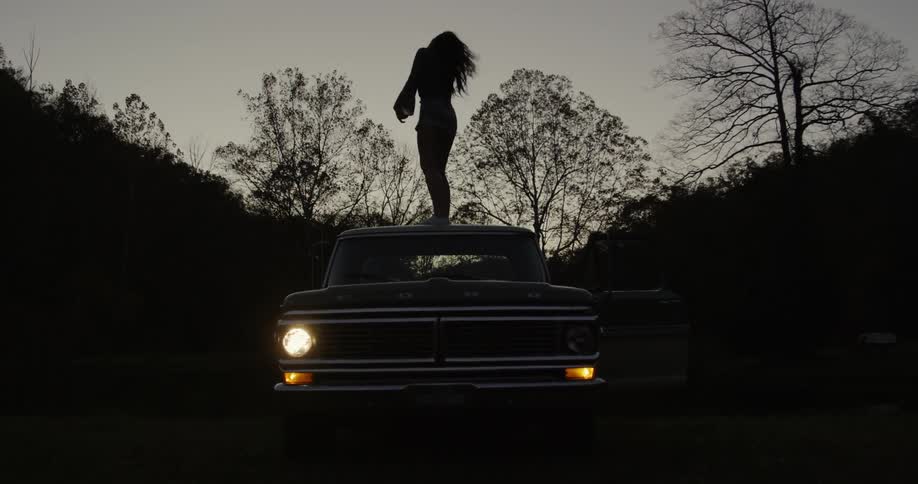 A woman dances on the top of a truck