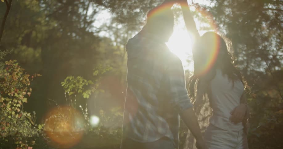 A man and woman dance together outside by the trees