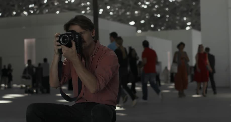 A man is taking photographs as people walk around