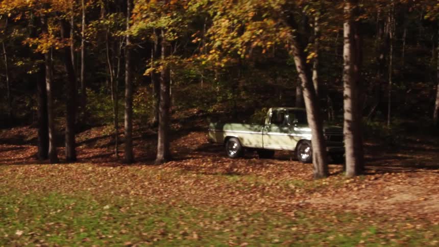 A truck drives through autumn trees