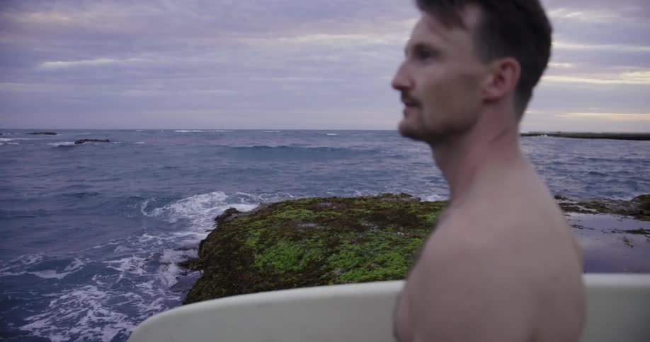 A man holding a surfboard looks at the water