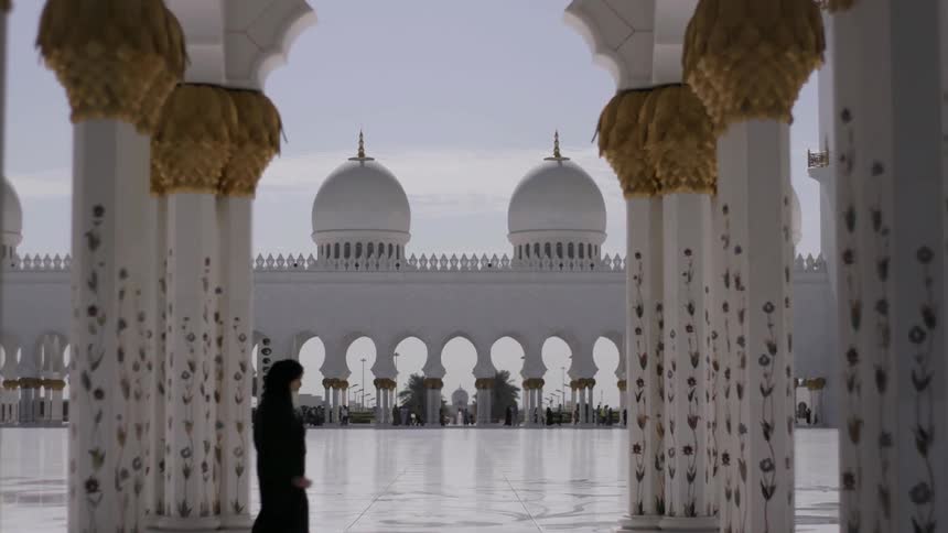 People walk around a large square near pillars