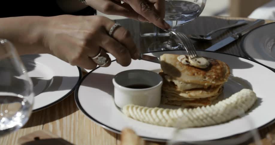 Person cuts into a pastry on a plate outside