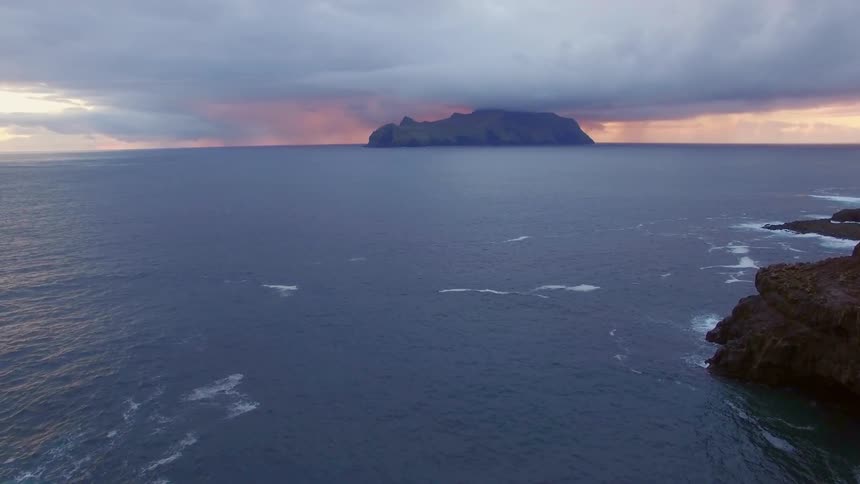 Person sits on a bench at the edge of a cliff overlooking a body of water