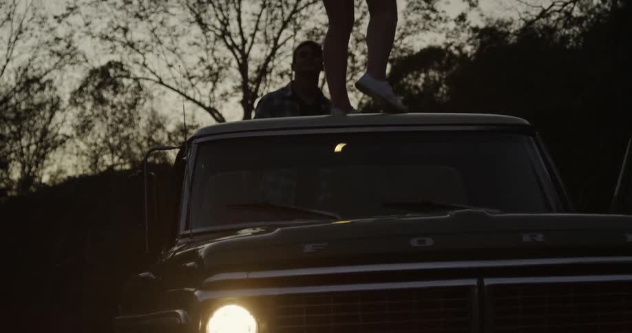 A woman is standing on a truck at dawn