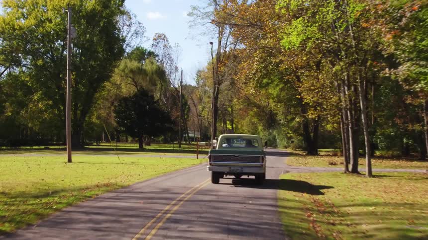 Truck drives down a tree lined country road