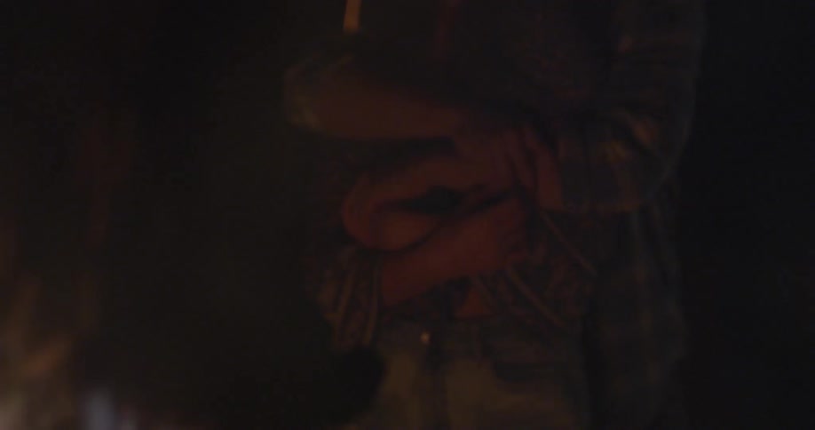 People hug near a campfire at night