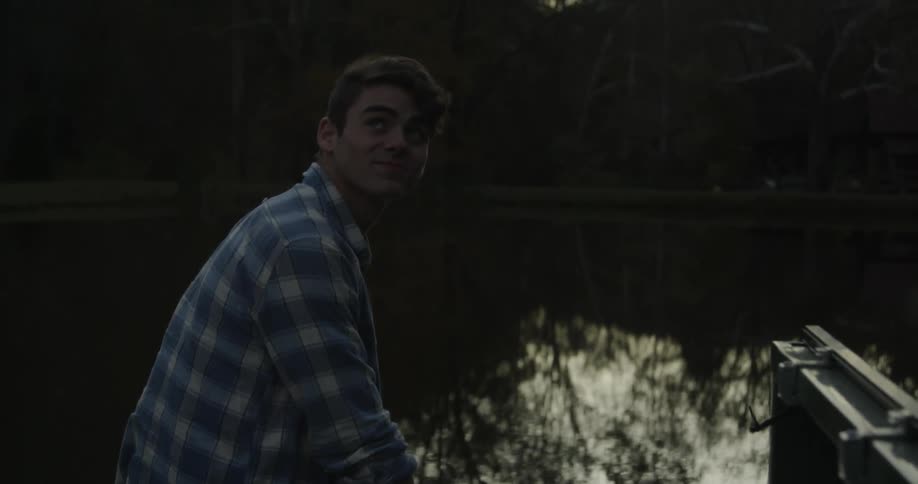 Smiling man sits at the edge of a lake