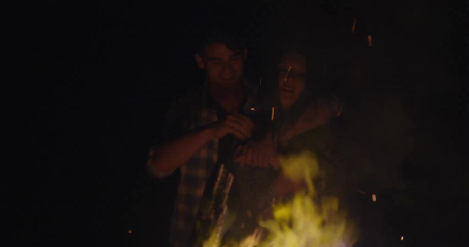 A man and woman embrace to the campfire