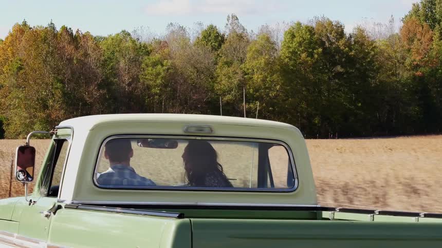 Man and woman in a pickup truck driving in the country