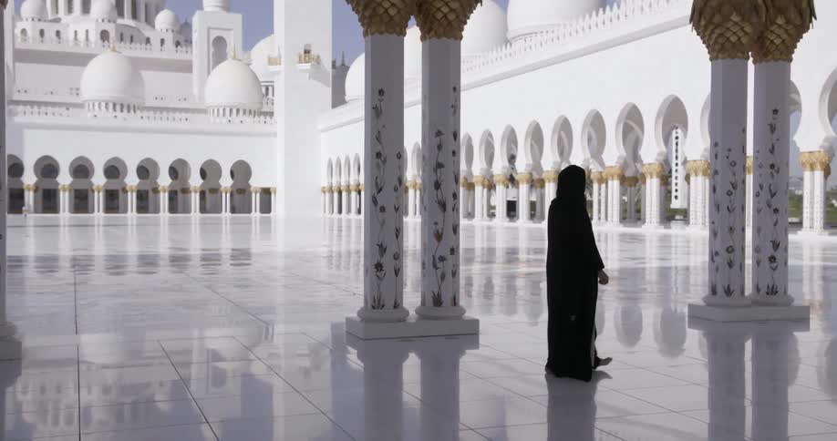 A woman walks in the tiled courtyard of a domed building