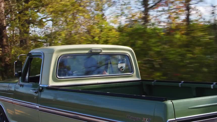 Two people riding in a truck down a country road near a lake