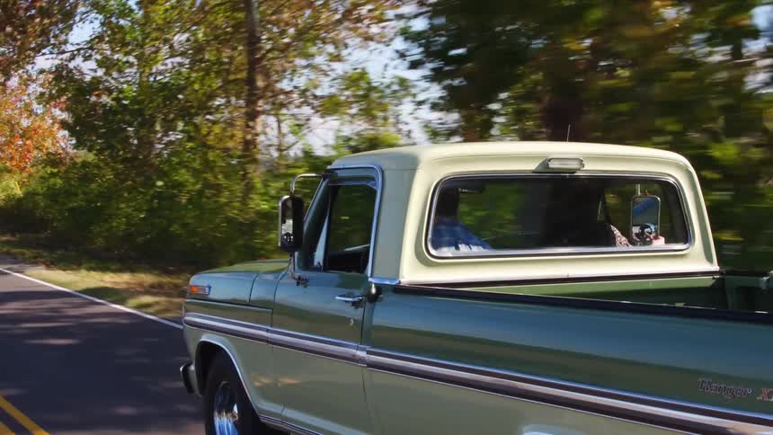 A couple travel in a pick up truck down a rural road