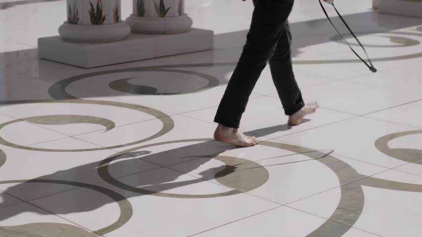 A man walks barefoot across a tiled floor