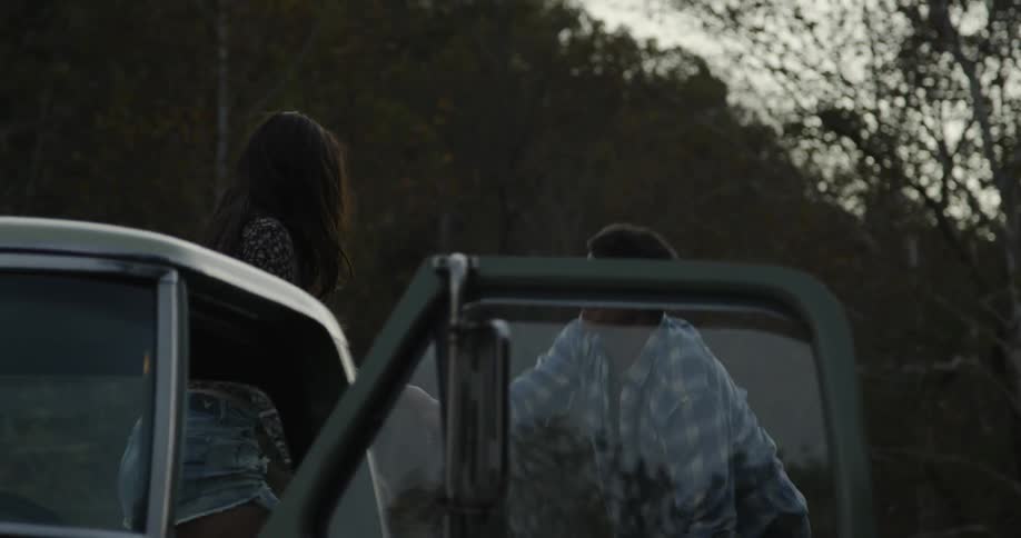 A man and woman climb into the truck of a bed