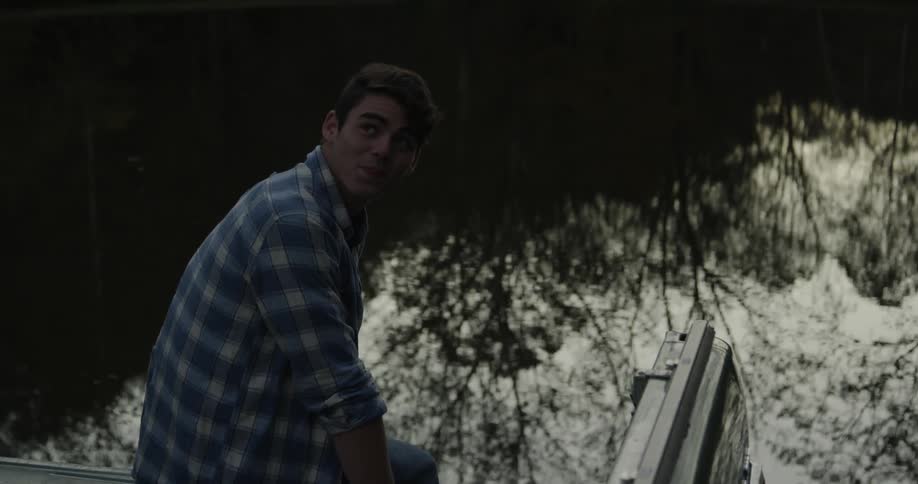 A man sits next to a rippling lake