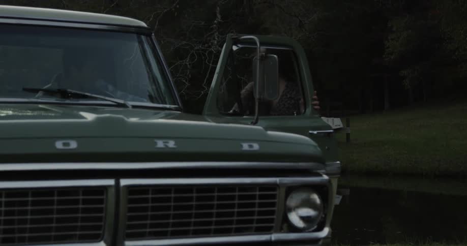 A woman helps a man out of an old pickup truck and they start to dance