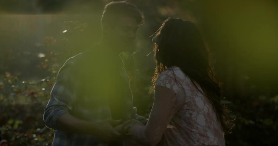 A man and woman play around by the trees