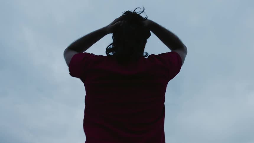 A man moves his hands down from his hair
