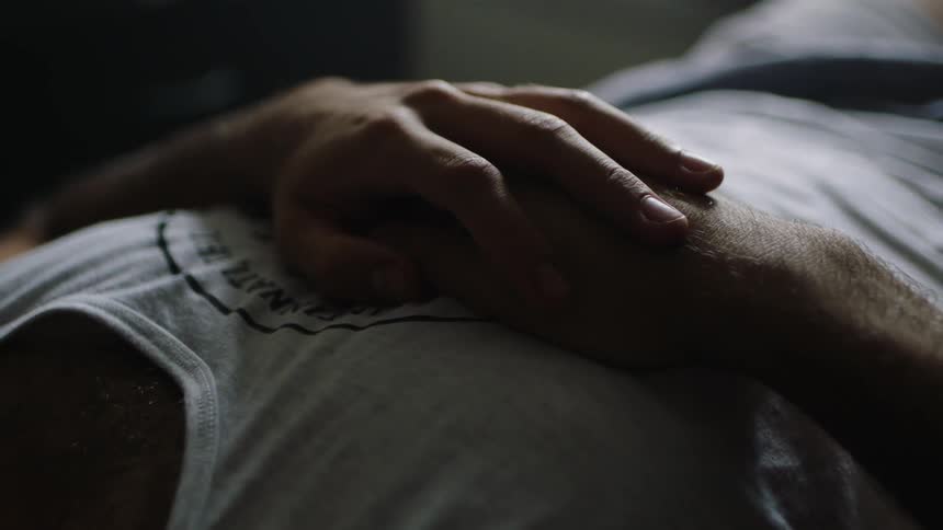 A man is laying down with his arms folded on his chest