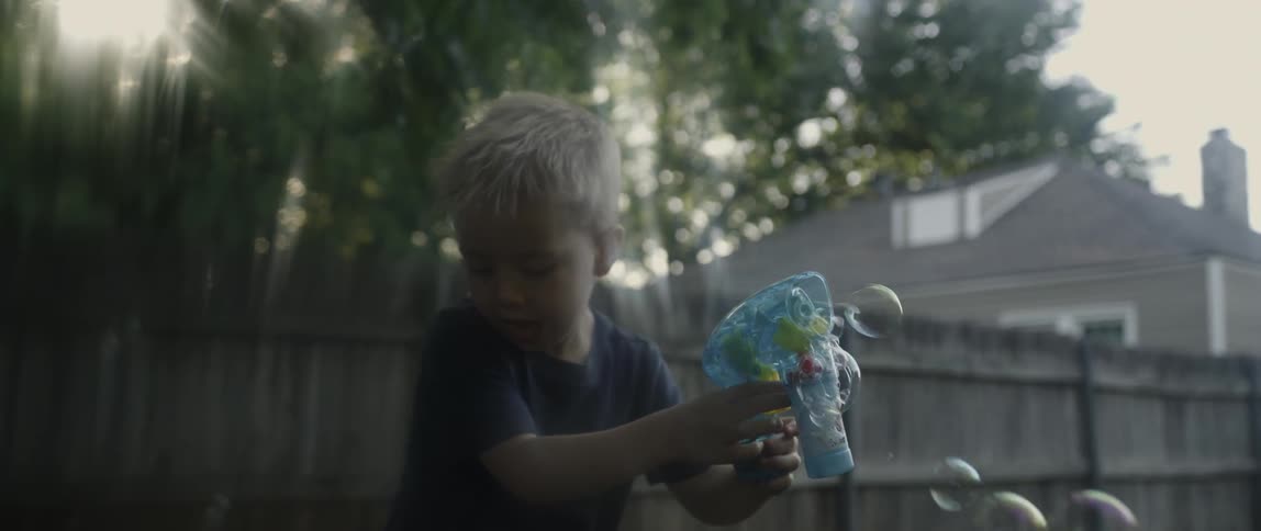 A boy is blowing bubbles with a gun