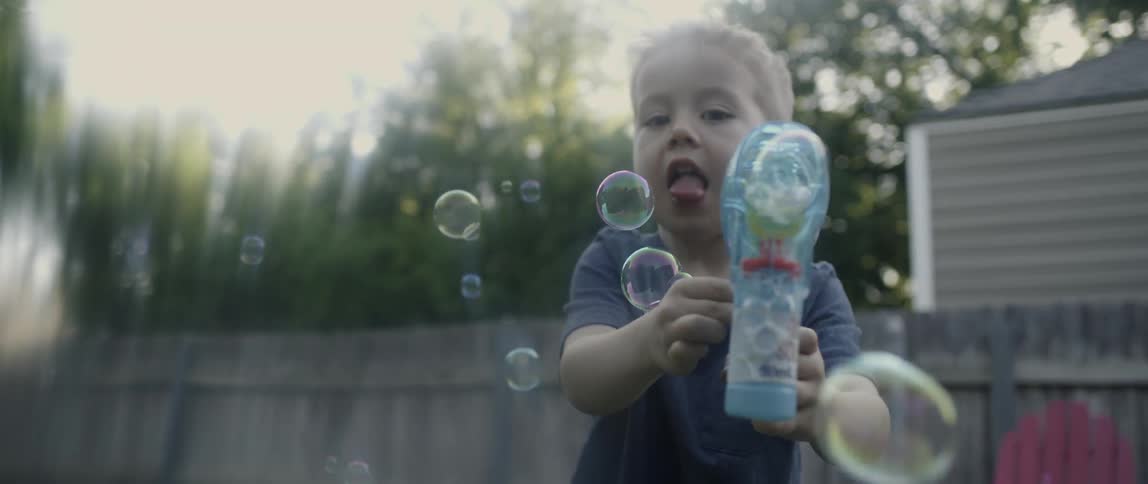 A young boy holds a bubble gun