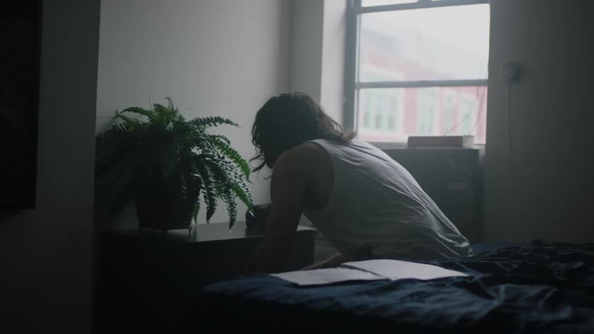 A man in a white shirt bobs his head to music near a window