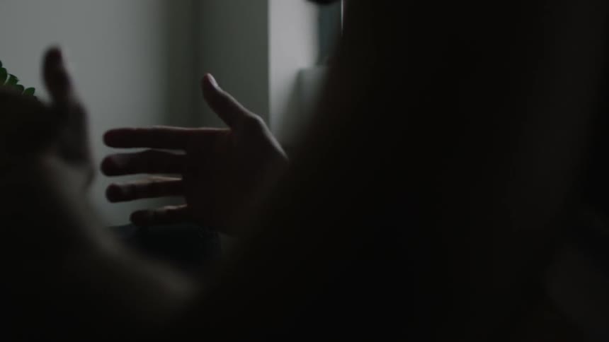 A man taps his hands sitting in the dark listening to music