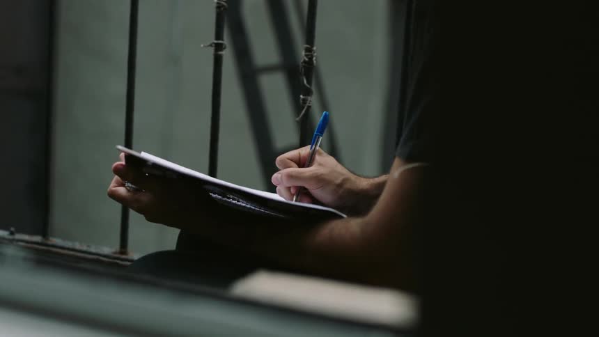 A person is writing with a pen in a notebook