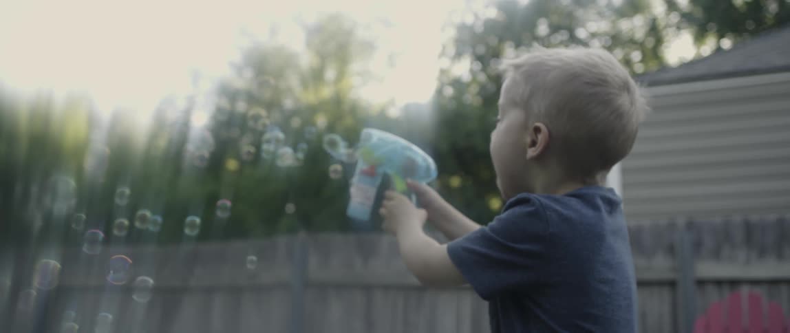 A boy is blowing bubbles with a toy