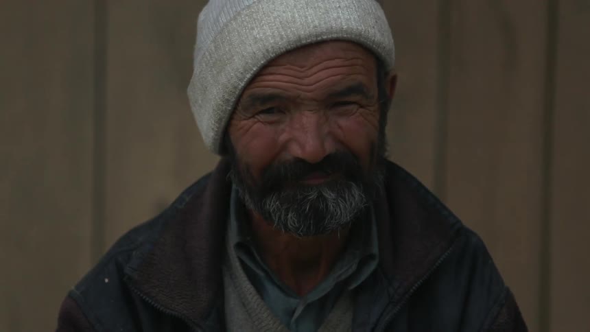 Old bearded man looks at camera