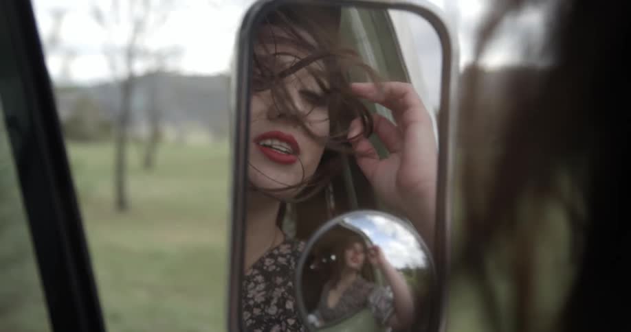 A woman's hair blows in the wind as she rides in a vehicle