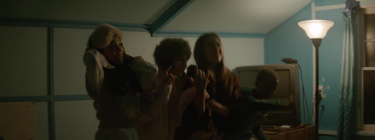 Four kids sing and bounce on a bed