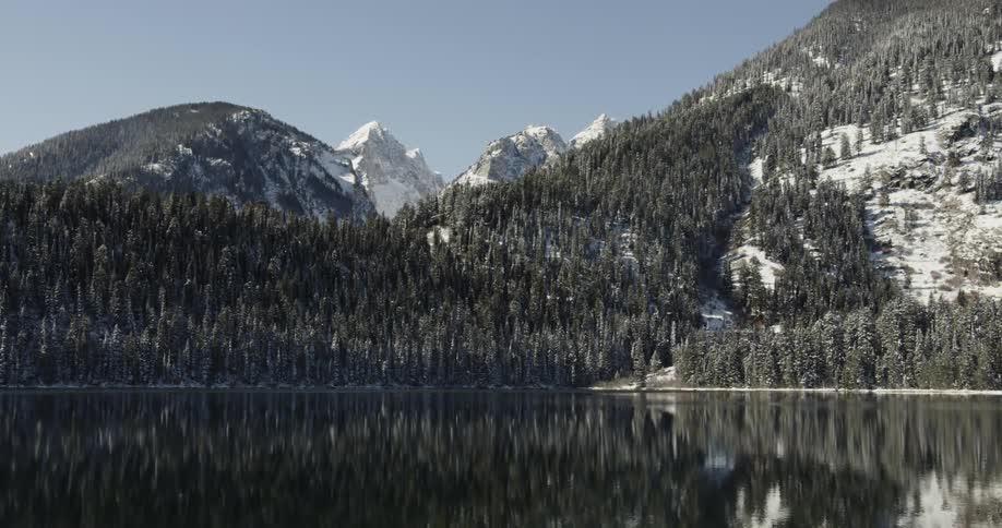 The water is very calm by the mountain