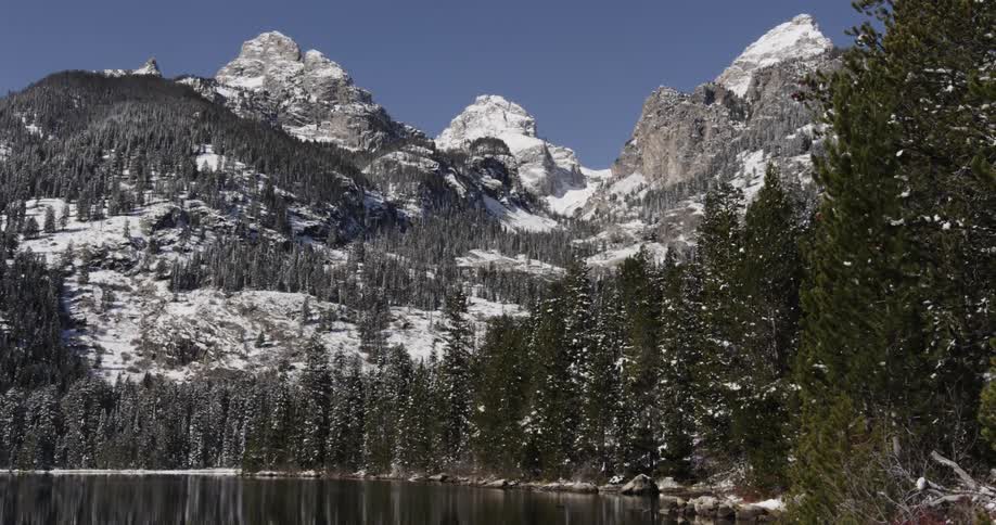 A lake beside a forest with mountains in the background