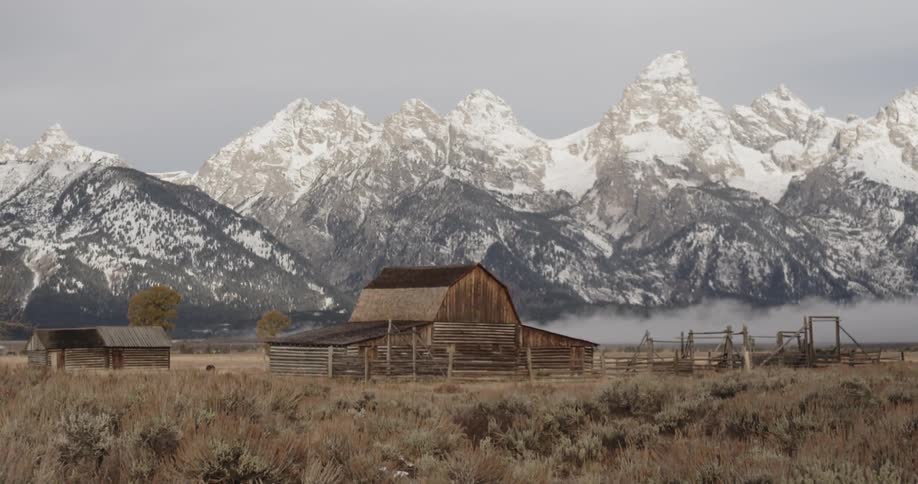 Deserted looking barn and snowy mountains