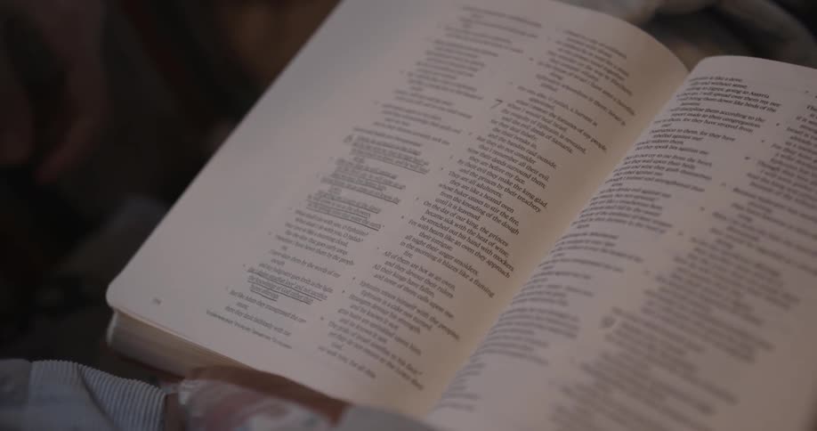 A woman slowly flipping pages of scripture in a bible