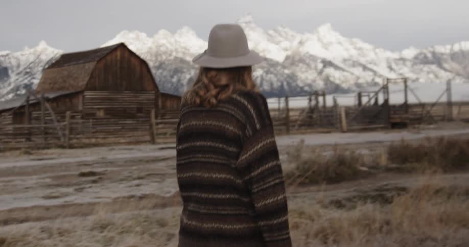 Woman walks past a deserted looking barn