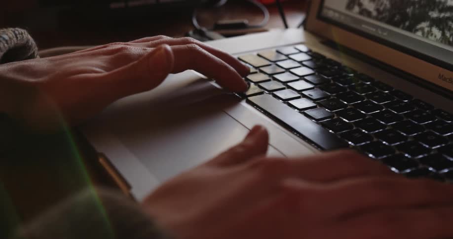 A woman scrolls through photographs on a laptop