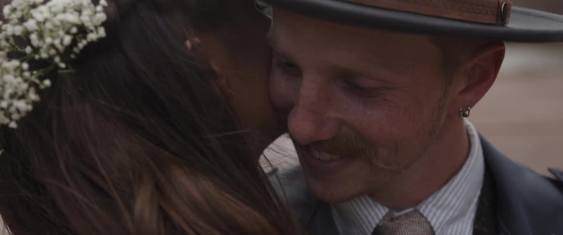 A man smiles as he nuzzles a woman