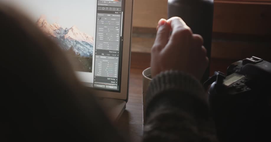 Woman stirs a mug with a tea bag in it next to a laptop