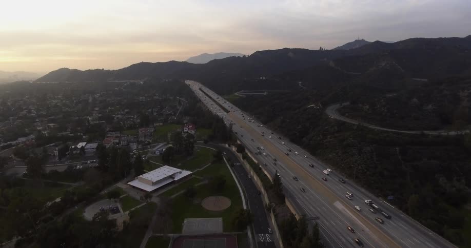 Cars speed down a highway next to a city