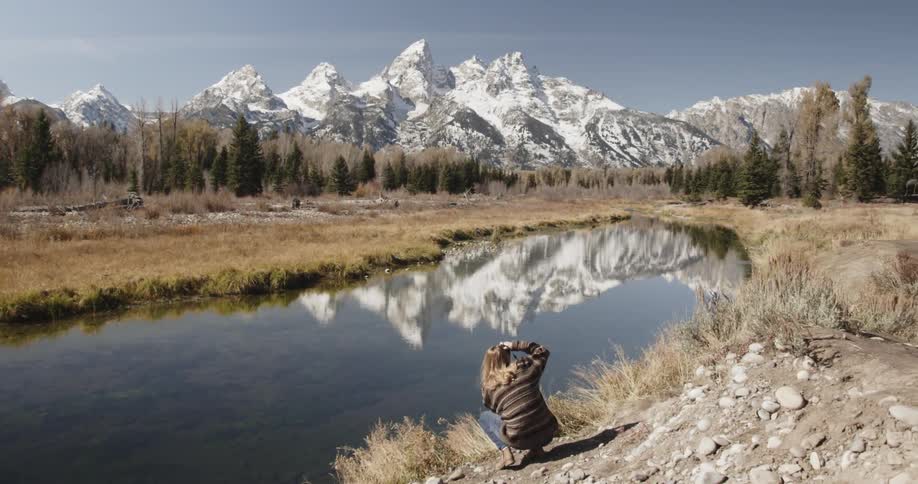 A woman takes pictures near a small lake