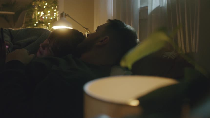 A man lays in bed with a person in his arms