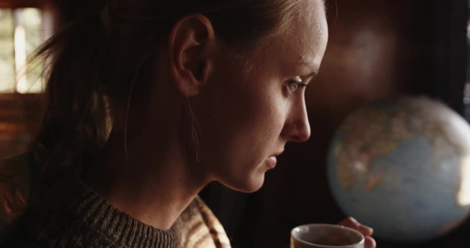 Woman sipping out of a mug next to a globe
