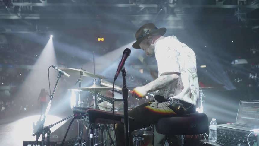 A drummer plays while a singer performs at a concert